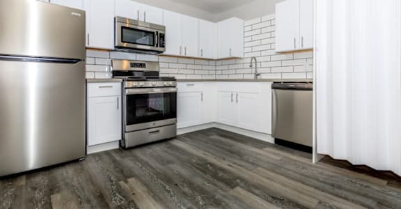 A kitchen with white cabinets and a stainless steel refrigerator.