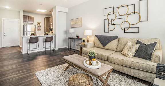 A living room with a beige couch, a white rug, and a ceiling fan.