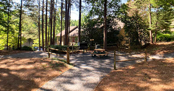 a campsite in the woods with a picnic table and grill