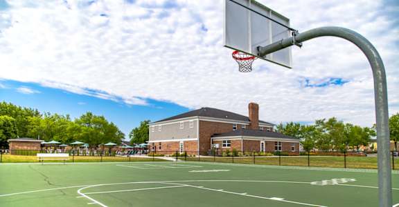 A basketball court with a hoop and a building in the background at Gramercy Apartments, Carmel Indiana