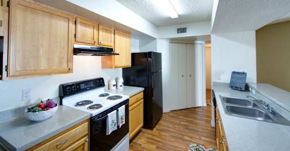 a kitchen with a black refrigerator freezer next to a stove top oven