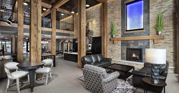 the lobby of a lodge with a fireplace and tables and chairs