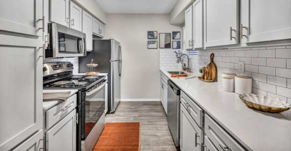 A kitchen with white cabinets and a wooden floor.