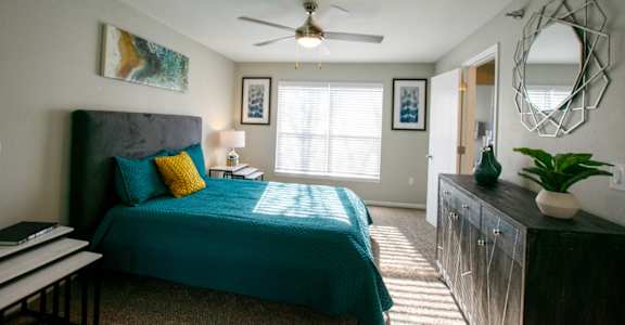 A bedroom with a bed, a dresser, and a mirror.