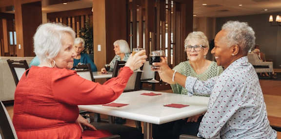 A group of elderly people are sitting around a table playing a card game.