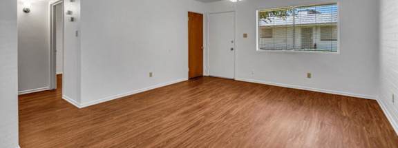 an empty living room with wood floors and a ceiling fan