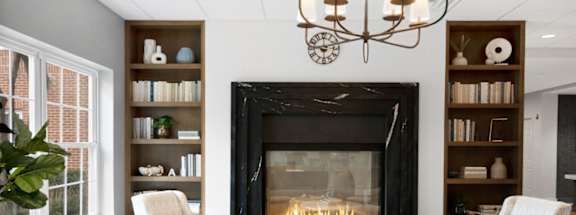 A living room with a fireplace, chairs, and a table.