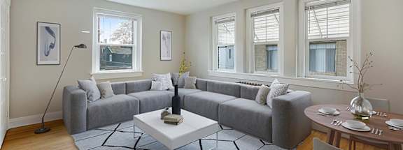 A living room with a grey couch, a white coffee table, and a ceiling fan.