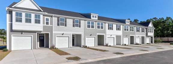 A row of townhouses with garages and a driveway in front.