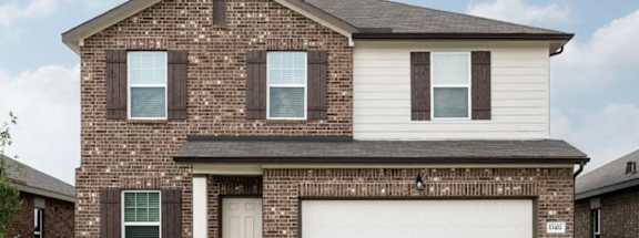 A two-story house with a garage door and a brick facade.
