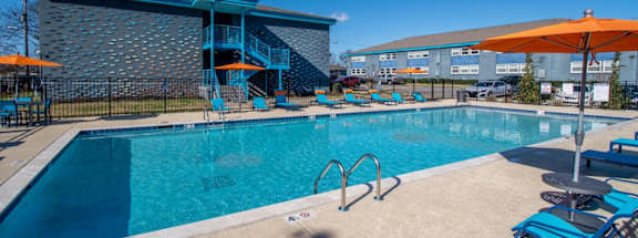 A large swimming pool at The Canvas Apartments East Nashville with a blue tiled building in the background.