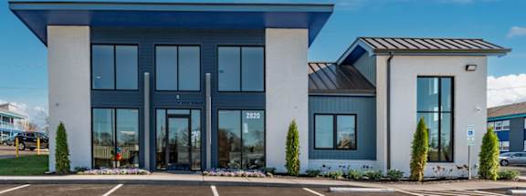 A modern leasing office building at The Canvas East Nashville Apartments with a blue roof and glass doors.