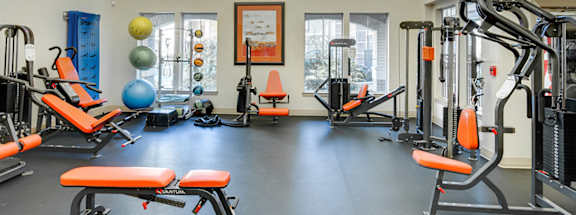 A gym with orange benches and a variety of equipment.