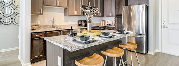 a kitchen with a large island with three stools in front of it at Ascend Apollo Apartments, Largo, MD