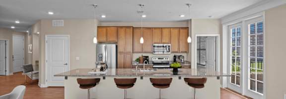 A modern kitchen with a bar stool and a white chair. at The Dorset, Kansas City, MO