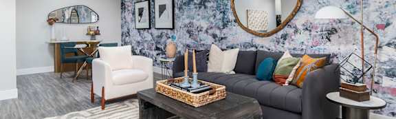 A living room with a grey couch, a wooden coffee table, and a round mirror on the wall. at The Heights Apartments, Cincinnati, 45220