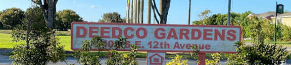 Deedco Gardens Signage with lush trees and bushes