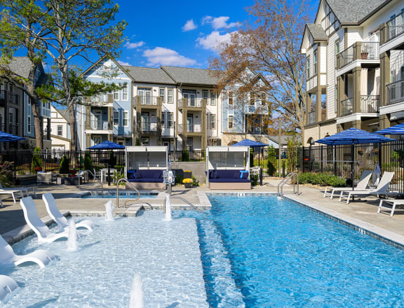 a swimming pool with chairs and umbrellas in front of an apartment building  at Oakbrook Townhomes, Tennessee