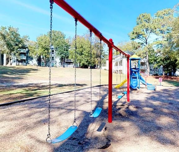 a swing set in a park with buildings in the background