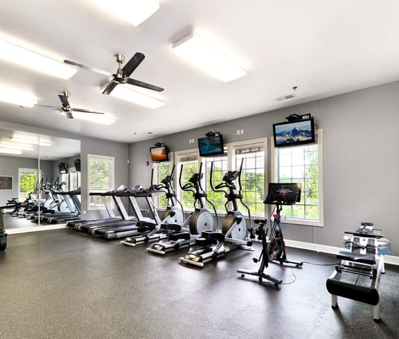 a room filled with lots of cardio equipment and a flat screen tv