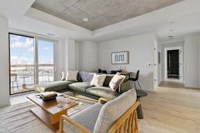 A living room with a couch, a coffee table, and a large window.