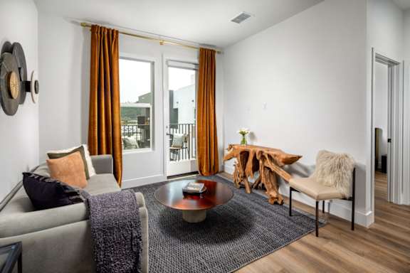 A living room with a couch and a patio entryway door at Vora Mission Valley East luxury apartments in San Diego.