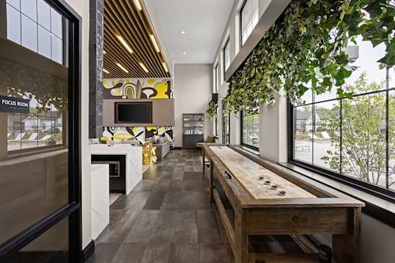 a long dining room with a wooden table and a large window at Slate at Fishers District, Fishers, 46037
