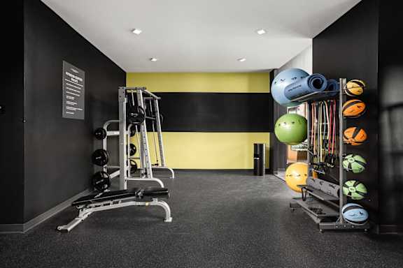 a gym with weights and equipment in a room with black and yellow walls at Slate at Fishers District, Fishers, 46037