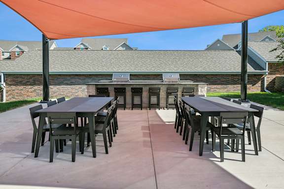 a patio with tables and chairs under an orange tent