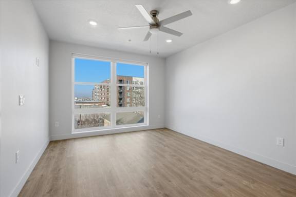 A room with a ceiling fan and a view of a building outside the window at Brickside Heights, Utah, 84106