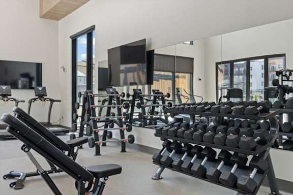 A gym with a variety of equipment including dumbbells and weight machines at Solhavn Apartments, American Fork, 84003
