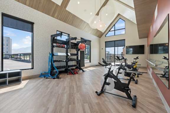 A gym with a row of exercise bikes and a weight rack at Solhavn Apartments, American Fork