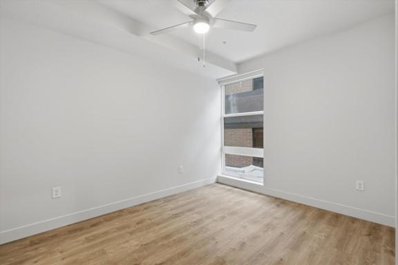 A room with a ceiling fan and a window with a view of a brick wall at Brickside Heights, Millcreek, UT