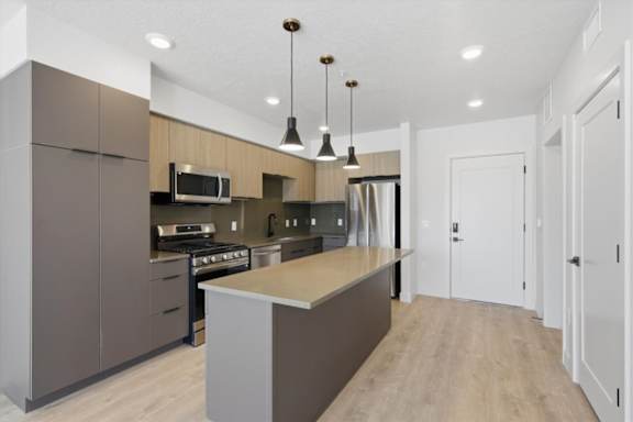 A modern kitchen with a large island in the middle at Brickside Heights, Millcreek, 84106