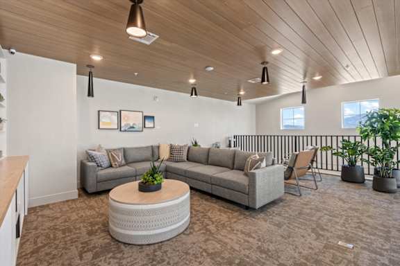 A living room with a grey couch, a coffee table, and a balcony with a railing at Solhavn Apartments, Utah, 84003