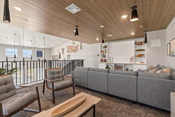 A modern living room with a grey sofa, wooden coffee table, and a wooden ceiling at Solhavn Apartments, American Fork, Utah