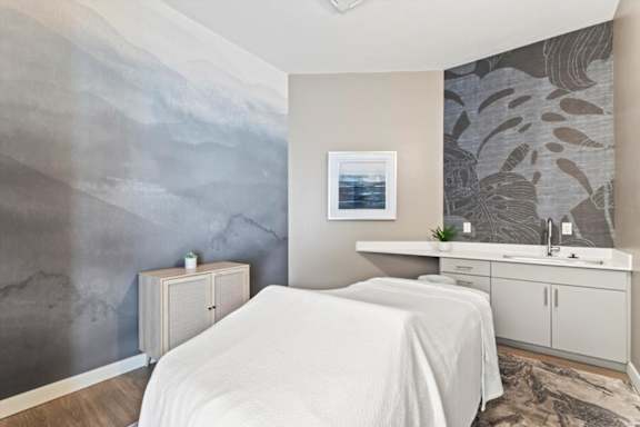 A bedroom with a white bed and a grey wallpapered wall.