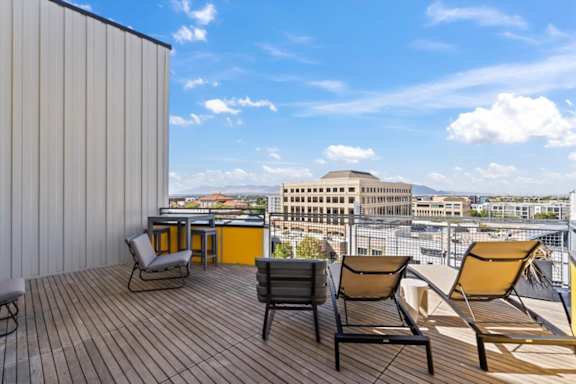 A balcony with chairs and a table overlooking a cityscape.