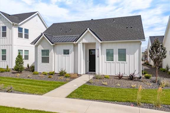 A white house with a black roof is surrounded by other similar houses. at Alante Homes at Spring Run, Idaho