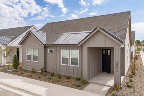 A grey house with a black door and a small garden in front. at Alante Homes at Spring Run, Caldwell, ID, 83607