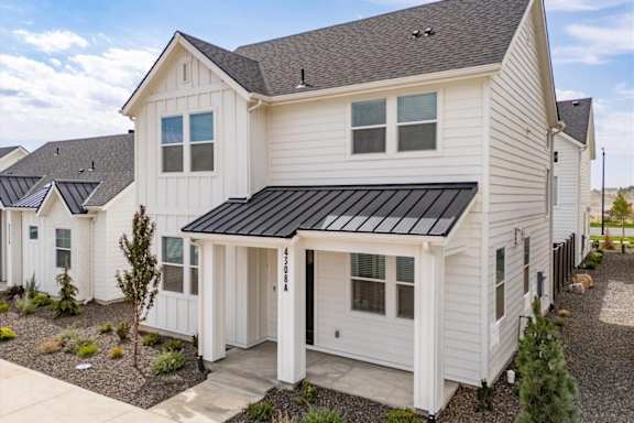 A white house with a black roof and a small tree in front. at Alante Homes at Spring Run, Caldwell, ID