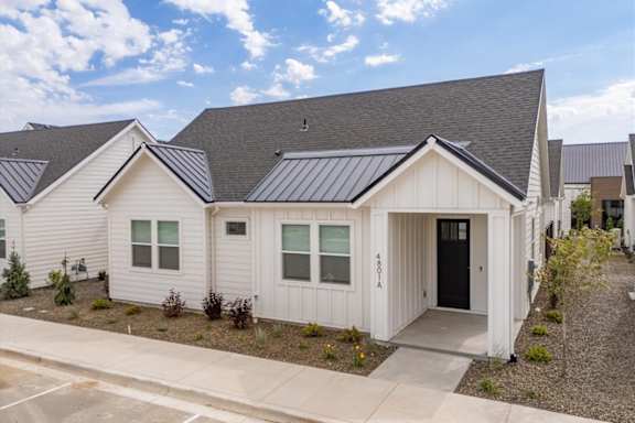 A white house with a black door and windows is surrounded by other similar houses. at Alante Homes at Spring Run, Caldwell, ID, 83607