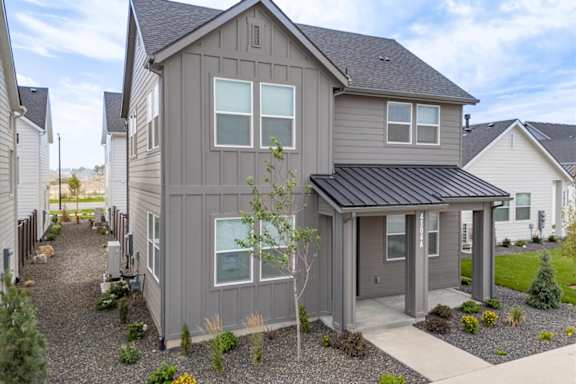 A grey house with a black roof and a gravel driveway. at Alante Homes at Spring Run, Caldwell, ID, 83607