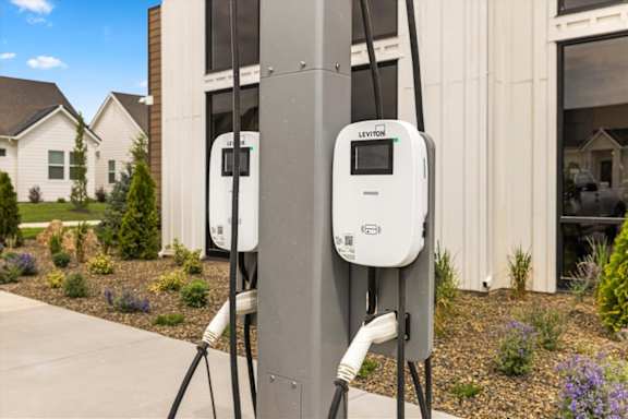 Two electric vehicle charging stations are installed on a pole outside a house. at Alante Homes at Spring Run, Caldwell, Idaho