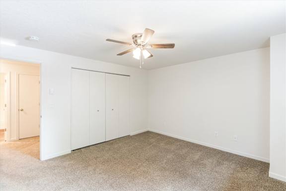 A room with a ceiling fan and carpeted floor.