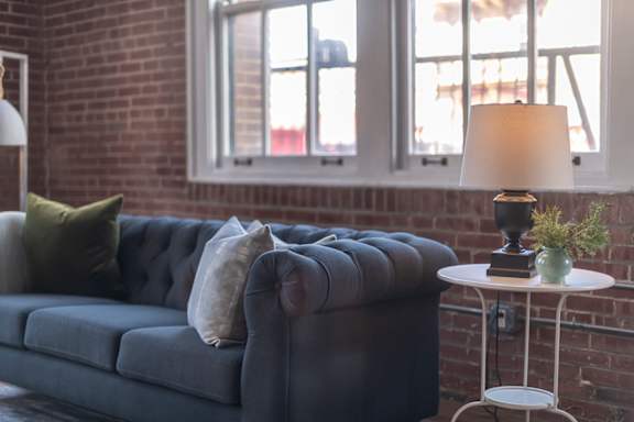 a living room with a blue couch and a brick wall