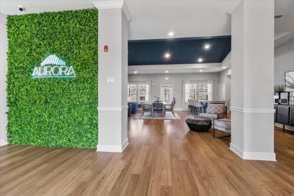 Aurora Apartments in Madison, AL clubhouse interior with a green wall and sign with tables and chairs