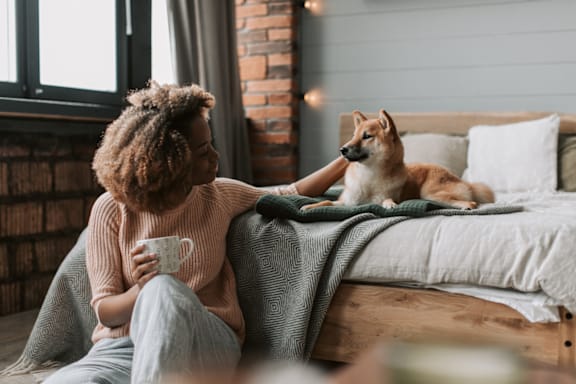 a woman sitting on a bed with her dog at Beacon Ridge Apartments, Greenville, SC, 29615