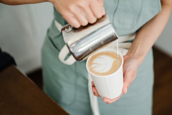 a person pouring a cup of coffee from a ninja coffee maker