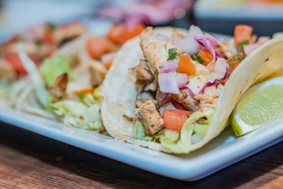 a plate of tacos with onions and tomatoes and a lime